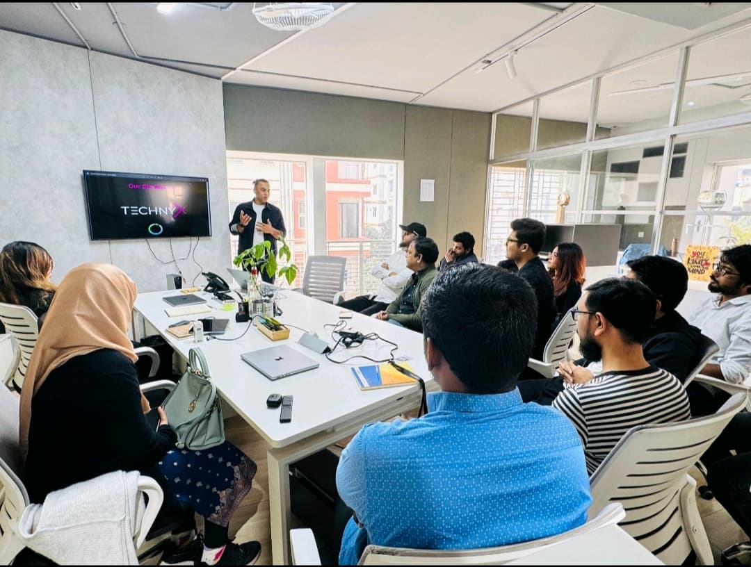 Technyx team meeting with presenter standing and discussing with colleagues